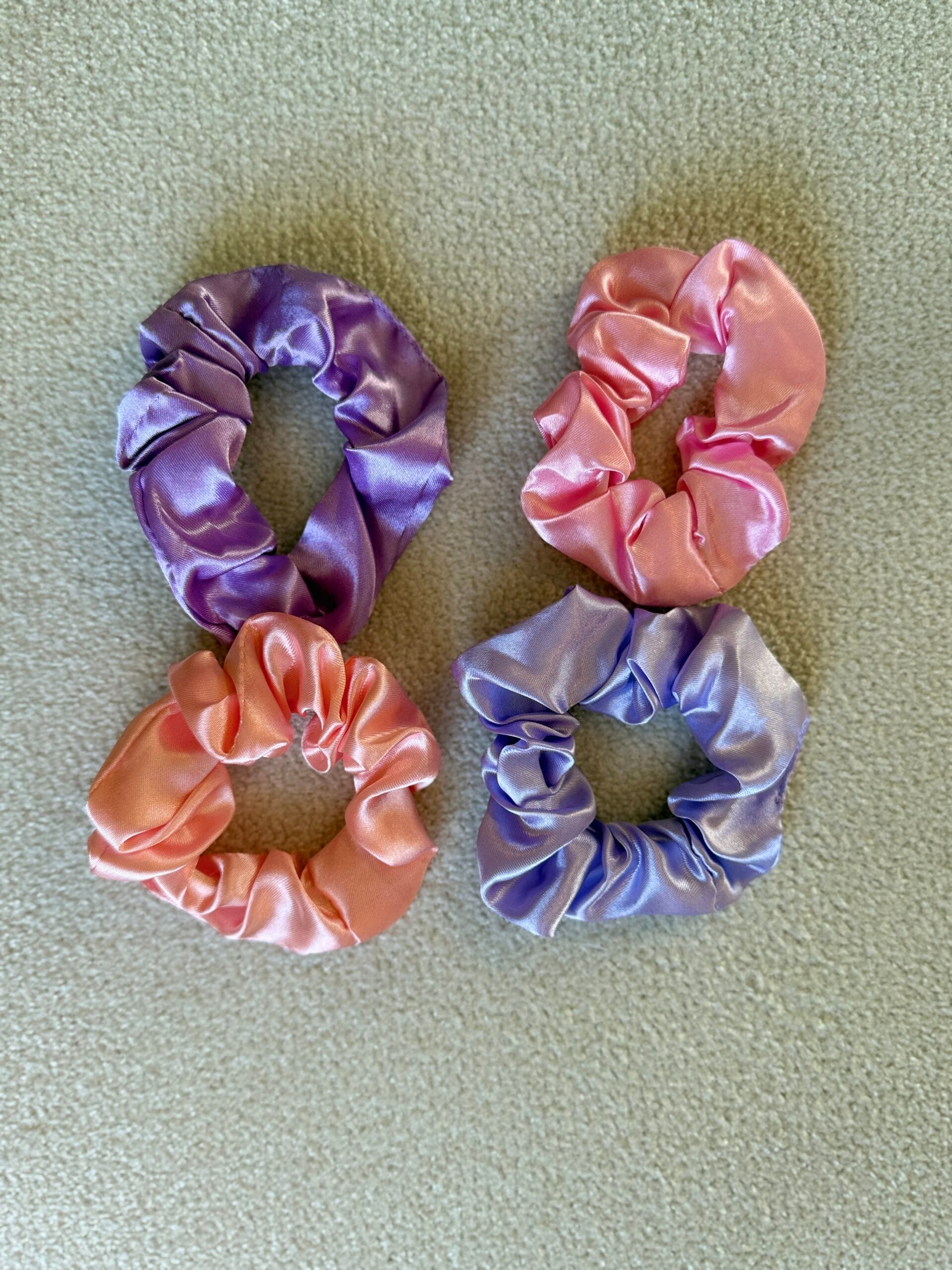 Mor ve şeftali tonlarında saten scrunchie’ler yakın çekim